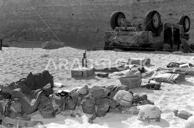 معدات من مركبة هامفي (HMMWV) متعددة الأغراض عالية الحركة M998 مقلوبة، ملقاة على الأرض. تظهر المركبة والجرف في الخلفية. الدولة: المملكة العربية السعودية.