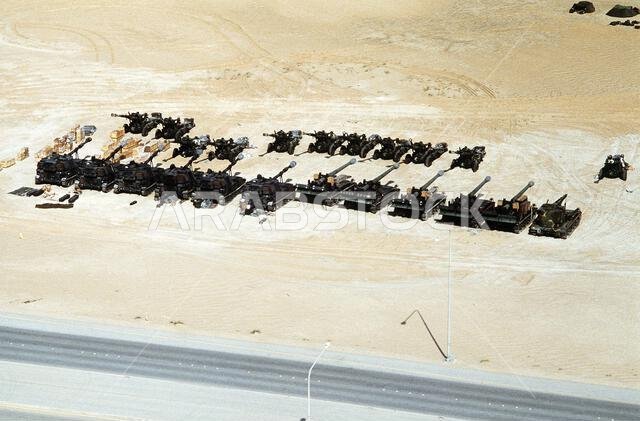 تصطف قطع المدفعية في صفوف في معسكر قاعدة قوة المشاة البحرية الأولى (I MEF) خلال عملية درع الصحراء. في المقدمة، تظهر مدافع هاوتزر ذاتية الدفع من طراز M-109 عيار 155 ملم، على اليسار، ومدافع هاوتزر ذاتية الدفع من طراز M-110A2 عيار 8 بوصات. وفي أقصى اليمين، تظهر مركبة إنقاذ مدرعة خفيفة من طراز M-578. وفي الخلفية، تظهر مدافع هاوتزر من طراز M-109 عيار 155 ملم. موضوع العملية/السلسلة: درع الصحراء. الدولة: المملكة العربية السعودية.