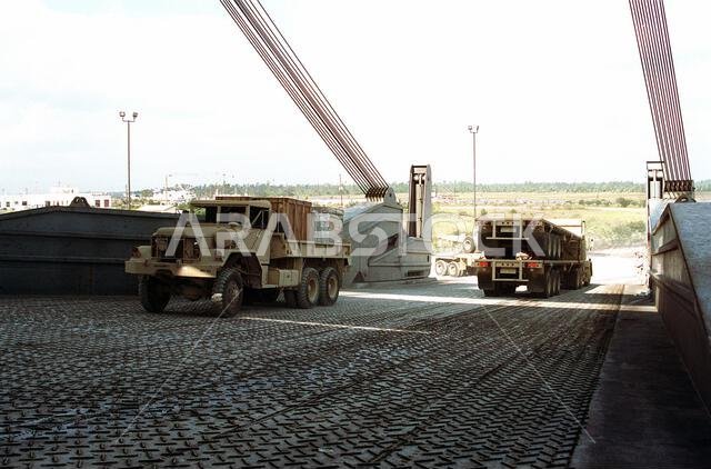 An M-54 5-ton cargo truck and a tractor trailer are driven onto the loading ramp of the Ready Reserve Fleet vehicle cargo ship CAPE HORN (T-AKR-5068). The equipment is being deployed to Saudi Arabia for use during Operation Desert Shield. Subject Operation/Series: DESERT SHIELD Base: Charleston State: South Carolina (SC) Country: United States Of America (USA)