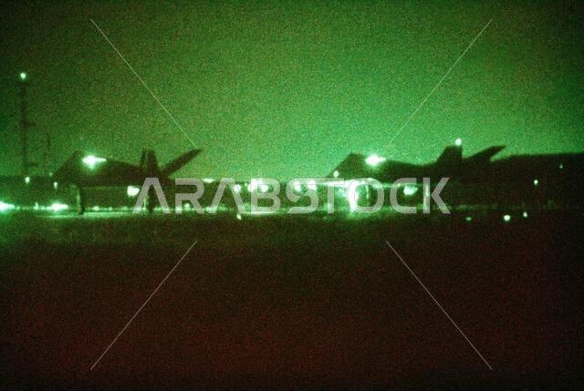 As seen through a night vision lens, two F-117A aircraft from the 37th Tactical Fighter Wing (37th TFW) taxi onto a runway during Operation Desert Shield. Subject Operation/Series: DESERT SHIELD Country: Saudi Arabia (SAU)