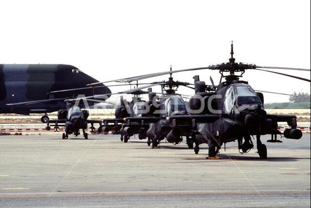 طائرة نقل عسكرية من طراز C-5A غالاكسي تسير على المدرج أمام صف من مروحيات AH-64 أباتشي خلال عملية درع الصحراء. العملية/السلسلة: درع الصحراء. الدولة: المملكة العربية السعودية. طائرة نقل عسكرية من طراز C-5A غالاكسي تسير على المدرج أمام صف من مروحيات AH-64 أباتشي خلال عملية درع الصحراء. العملية/السلسلة: درع الصحراء. الدولة: المملكة العربية السعودية.