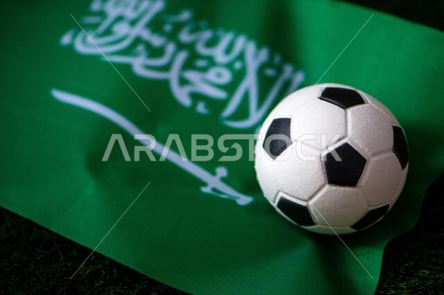 منتخب المملكة العربية السعودية لكرة القدم. العلم الوطني على العشب الأخضر وكرة القدم. خلفية كرة قدم لبطولة كأس العالم 2022.
