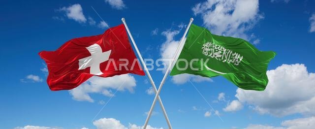 علمان متقاطعان، علم السعودية وعلم سويسرا، يرفرفان في مهب الريح تحت سماء ملبدة بالغيوم. يرمز هذا العمل الفني إلى مفهوم العلاقة والحوار والسفر بين البلدين. رسم ثلاثي الأبعاد
