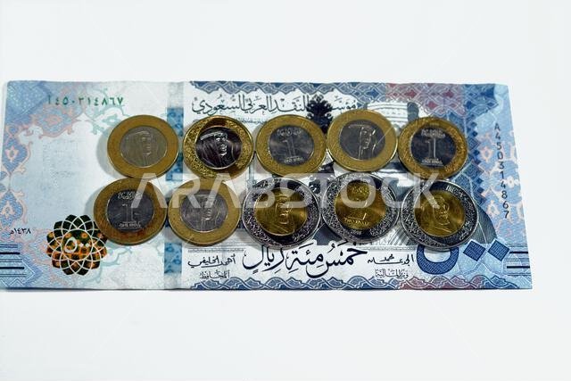 ورقة نقدية من فئة 500 ريال سعودي مع رزمة من العملات المعدنية من فئة ريال واحد وريالين، تحمل صورة الملك سلمان بن عبد العزيز آل سعود. ورقة نقدية من فئة 500 ريال سعودي مع رزمة من العملات المعدنية من فئة ريال واحد وريالين، تحمل صورة الملك سلمان بن عبد العزيز آل سعود.