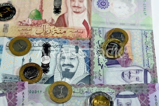 Saudi Arabia riyals money banknotes and coins, a pile of 500 SAR, 100 Saudi riyals and 5 riyals with 1, 2 riyals coins features king Salman bin AbdulA