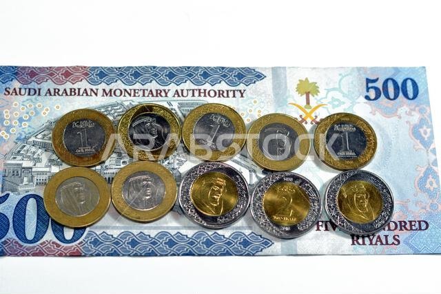 500 SAR five hundred Saudi Arabia riyals cash money banknote with pile of Saudi riyal coins 1 and 2 riyals features king Salman Bin AbdulAziz Al Saud