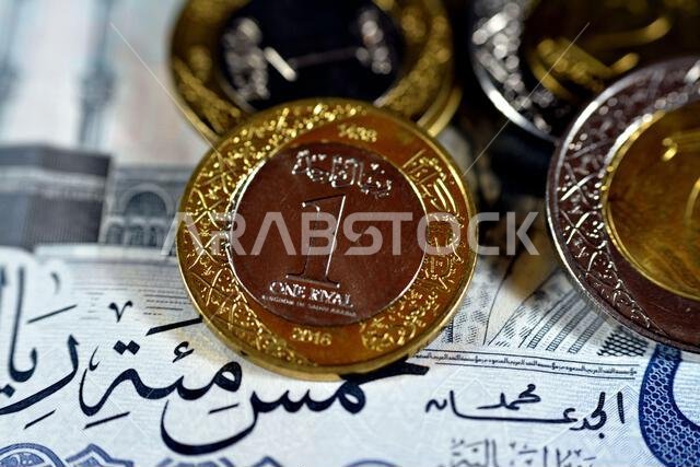Reverse side of 1 SAR one Saudi Arabia riyals coin series 1438 AH 2016 isolated with other Saudi coins on 500 SAR five hundred riyals banknote money,
