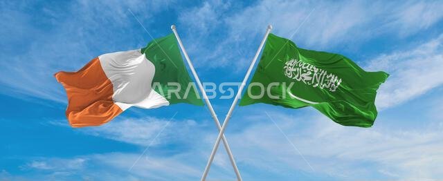 علمان متقاطعان، علم السعودية وعلم أيرلندا، يرفرفان في مهب الريح تحت سماء ملبدة بالغيوم. يرمز هذا العمل الفني إلى مفهوم العلاقة والحوار والسفر بين البلدين. رسم ثلاثي الأبعاد.