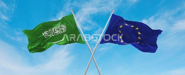 two crossed flags The European Union and Saudi Arabia waving in wind at cloudy sky. Concept of relationship, dialog, travelling between two countries.