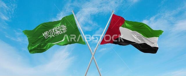 two crossed flags United Arab Emirates and Saudi Arabia waving in wind at cloudy sky. Concept of relationship, dialog, travelling between two countrie