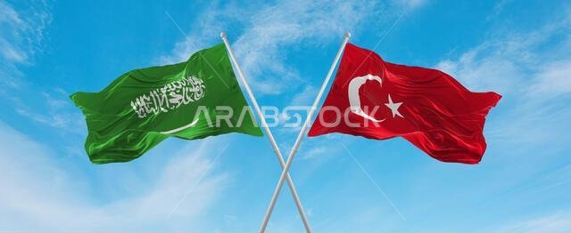 علمان متقاطعان، علم تركيا وعلم السعودية، يرفرفان في مهب الريح تحت سماء ملبدة بالغيوم. يرمز هذا العمل الفني إلى مفهوم العلاقة والحوار والسفر بين البلدين. رسم ثلاثي الأبعاد.