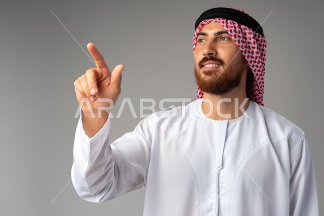 Young Arab man pointing hand to copy space on gray background