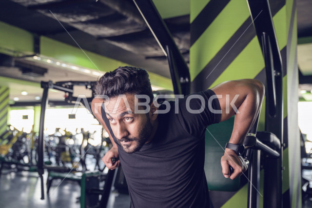 شاب سعودي رياضي يقوم بتمرين العقلة  السحب للأعلى في النادي