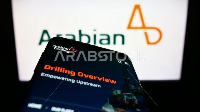 هاتف محمول يعرض موقع شركة الحفر العربية السعودية (ADC) أمام الشعار. ركّز على الزاوية العلوية اليسرى من شاشة الهاتف. هاتف محمول يعرض موقع شركة الحفر العربية السعودية (ADC) أمام الشعار. ركّز على الزاوية العلوية اليسرى من شاشة الهاتف.