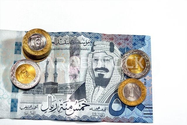 ورقة نقدية من فئة 500 ريال سعودي مع رزمة من العملات المعدنية من فئة ريال واحد وريالين، تحمل صورة الملك سلمان بن عبد العزيز آل سعود. ورقة نقدية من فئة 500 ريال سعودي مع رزمة من العملات المعدنية من فئة ريال واحد وريالين، تحمل صورة الملك سلمان بن عبد العزيز آل سعود.