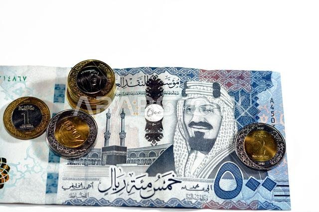 ورقة نقدية من فئة 500 ريال سعودي مع رزمة من العملات المعدنية من فئة ريال واحد وريالين، تحمل صورة الملك سلمان بن عبد العزيز آل سعود. ورقة نقدية من فئة 500 ريال سعودي مع رزمة من العملات المعدنية من فئة ريال واحد وريالين، تحمل صورة الملك سلمان بن عبد العزيز آل سعود.