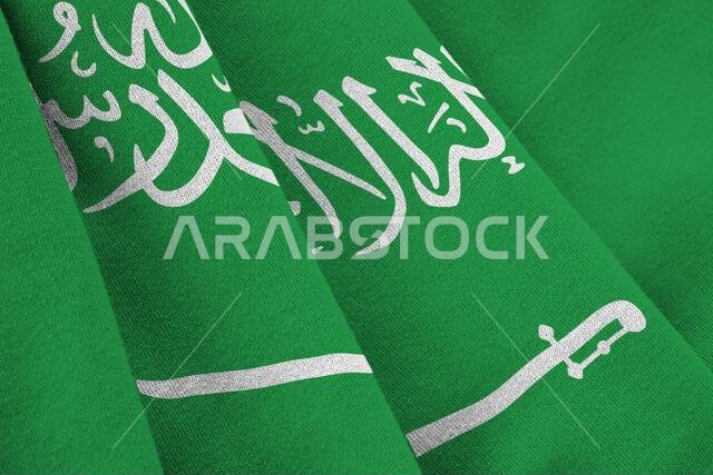 Saudi Arabia flag with big folds waving close up under the studio light indoors. The official symbols and colors in fabric banner