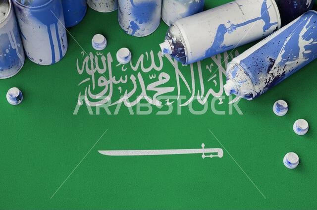 Saudi Arabia flag and few used aerosol spray cans for graffiti painting. Street art culture concept, vandalism problems