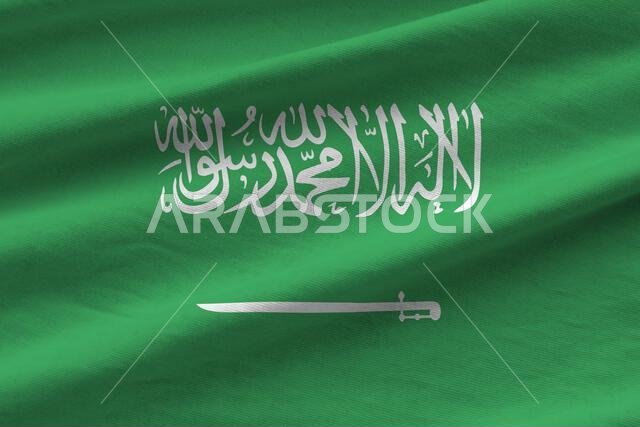 Saudi Arabia flag with big folds waving close up under the studio light indoors. The official symbols and colors in fabric banner