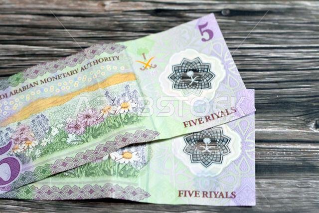 Reverse side of the new polymer 5 SAR five Saudi Arabia riyals cash money banknote bill series 1441 AH 2020 features a field of flowers, selective foc