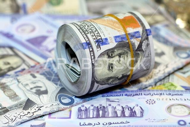لفة نقود أمريكية عليها شريط، وكومة من أوراق الدولار الأمريكي، وأوراق نقدية أمريكية مع أوراق نقدية من الريال السعودي والإمارات الجديدة. لفة نقود أمريكية عليها شريط، وكومة من أوراق الدولار الأمريكي، وأوراق نقدية أمريكية مع أوراق نقدية من الريال السعودي والإمارات الجديدة.