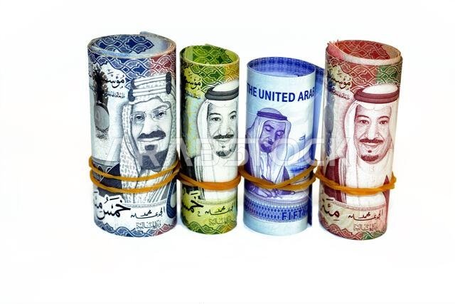 لفائف من الأوراق النقدية من فئة 50 ريالاً سعودياً، و50 درهماً إماراتياً، و500 ريالاً، و100 ريال.