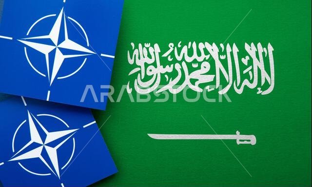 LONDON, UK - August 2022: NATO North Atlantic Treaty Organization military alliance logo on a Saudi arabia flag