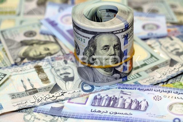 لفة نقود أمريكية عليها شريط، وكومة من أوراق الدولار الأمريكي، وأوراق نقدية أمريكية مع أوراق نقدية من الريال السعودي والإمارات الجديدة. لفة نقود أمريكية عليها شريط، وكومة من أوراق الدولار الأمريكي، وأوراق نقدية أمريكية مع أوراق نقدية من الريال السعودي والإمارات الجديدة.