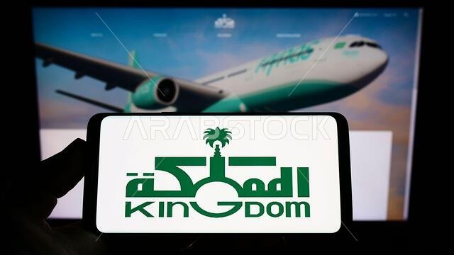 شخص يحمل هاتفًا ذكيًا عليه شعار شركة المملكة العربية السعودية القابضة (KHC) على الشاشة أمام موقع إلكتروني. التركيز على شاشة الهاتف. شخص يحمل هاتفًا ذكيًا عليه شعار شركة المملكة العربية السعودية القابضة (KHC) على الشاشة أمام موقع إلكتروني. التركيز على شاشة الهاتف.