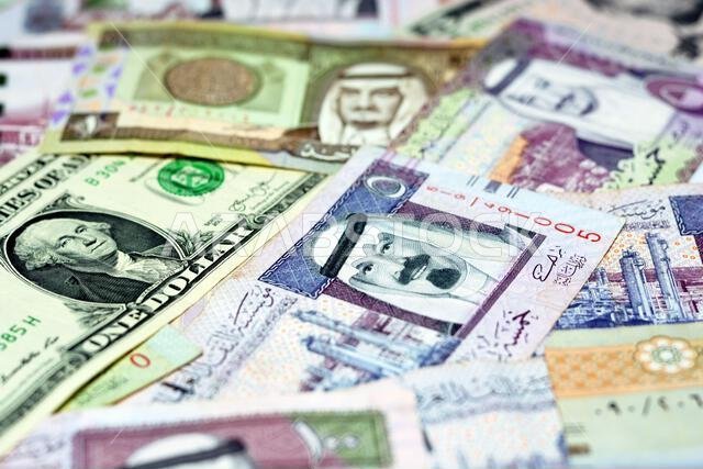 أوراق نقدية من الريال السعودي مع أوراق نقدية من الدولار الأمريكي، تركيز انتقائي على الريال السعودي، ودولار الولايات المتحدة الأمريكية