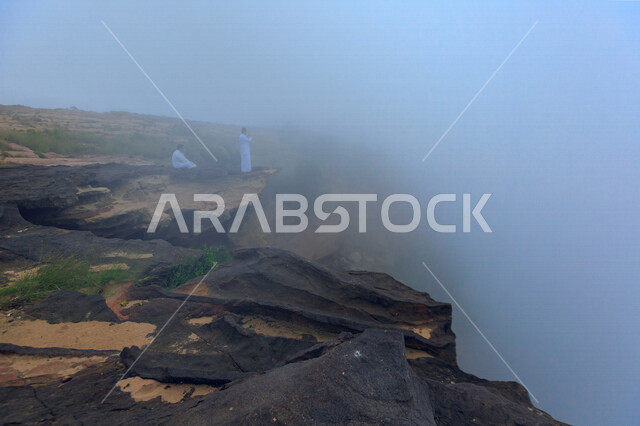 صورة ابداعية لرجلان عربيان خليجيان سعوديان فوق قمة جبلية في المملكة العربية السعودية، صعود الجبال، الجبال الصخرية، مناظر طبيعية خلابة، رحلة ترفيهية