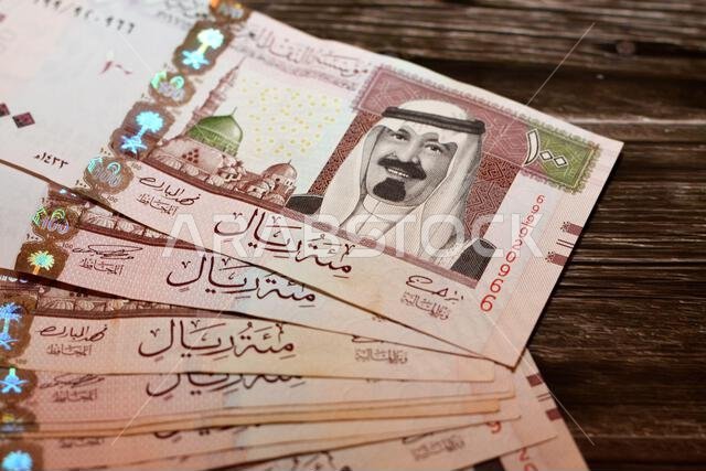 رزمة من الأوراق النقدية السعودية فئة 100 ريال سعودي، تحمل صورة الملك عبد الله بن عبد العزيز آل سعود والمسجد النبوي في المدينة المنورة.
