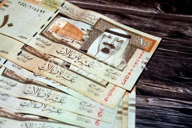 كومة من أوراق نقدية سعودية من فئة 10 ريالات سعودية، تحمل صورة الملك عبد الله بن عبد العزيز آل سعود وقصر المربع، معزولة على
