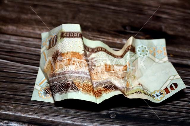 ورقة نقدية سعودية مجعدة من فئة 10 ريالات، معزولة على خلفية خشبية، ورقة نقدية سعودية مجعدة من فئة 10 ريالات، تضخم العملة السعودية