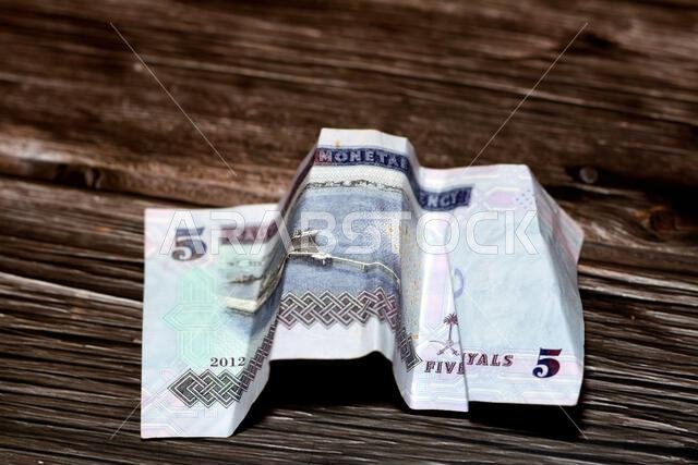 Crumpled Saudi Arabia money of 5 SAR five riyals isolated on wooden background, wrinkled 5 Saudi Riyals cash bill banknote, Saudi money inflation and