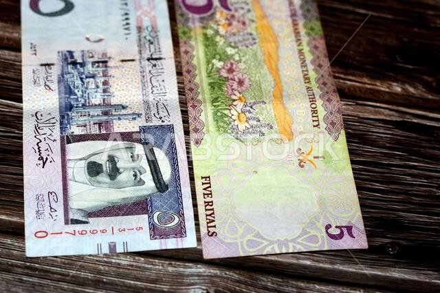 Saudi Arabia 5 SAR five Saudi riyals cash money banknote with the photo of king Abdullah bin AbdulAziz Al Saud and Flowers isolated on a wood backgrou
