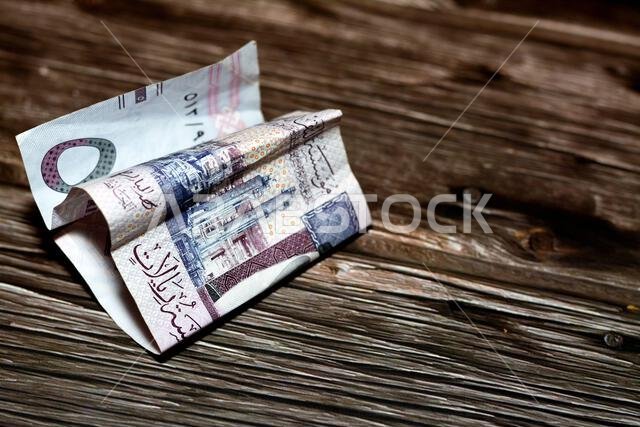 Folded Saudi Arabia money of 5 SAR five riyals isolated on wooden background, wrinkled 5 Saudi Riyals cash bill banknote, Saudi money inflation and ec