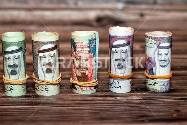 أوراق نقدية من فئة الريال السعودي ملفوفة بأربطة مطاطية، من فئات 100 و50 و20 ريالاً.