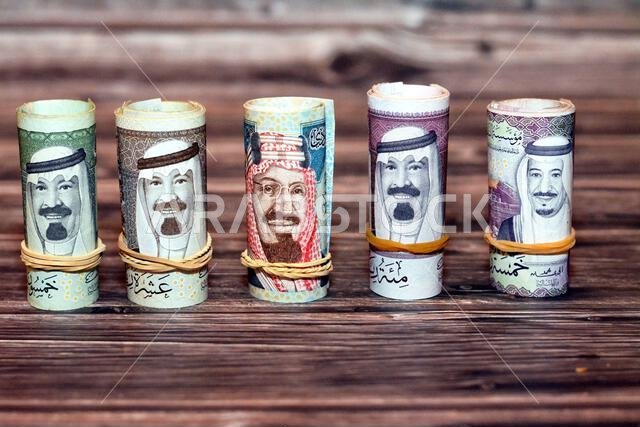 Saudi Arabia money roll riyals banknotes isolated on wooden background, Saudi riyals cash money bills rolled up with rubber bands of 100 SAR, 50, 20, Saudi Arabia money roll riyals banknotes isolated on wooden background, Saudi riyals cash money bills rolled up with rubber bands of 100 SAR, 50, 20,