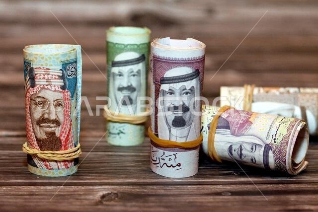 أوراق نقدية من فئة الريال السعودي ملفوفة بأربطة مطاطية، من فئات 100 و50 و20 ريالاً.