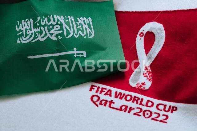 QATAR, DOHA, 18 JULY, 2022: Saudi Arabia National flag and logo of FIFA World Cup in Qatar 2022 on red carpet. Soccer sport background, edit space. Qa
