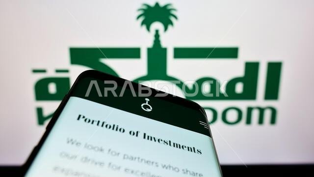Mobile phone with webpage of Saudi Arabian Kingdom Holding Company (KHC) on screen in front of business logo. Focus on top-left of phone display.
