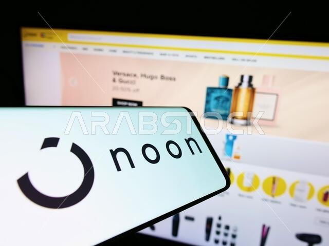 هاتف ذكي يعرض شعار شركة التجارة الإلكترونية "نون إيه دي هولدينغز المحدودة" على شاشته أمام موقع الشركة الإلكتروني. التركيز على الجانب الأيمن من شاشة الهاتف. هاتف ذكي يعرض شعار شركة التجارة الإلكترونية "نون إيه دي هولدينغز المحدودة" على شاشته أمام موقع الشركة الإلكتروني. التركيز على الجانب الأيمن من شاشة الهاتف.
