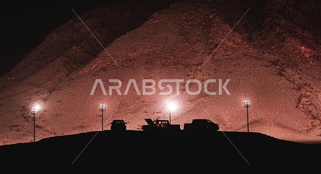Silhouette of people camping near a mountain park at night, An image from Bisha, Saudi Arabia.