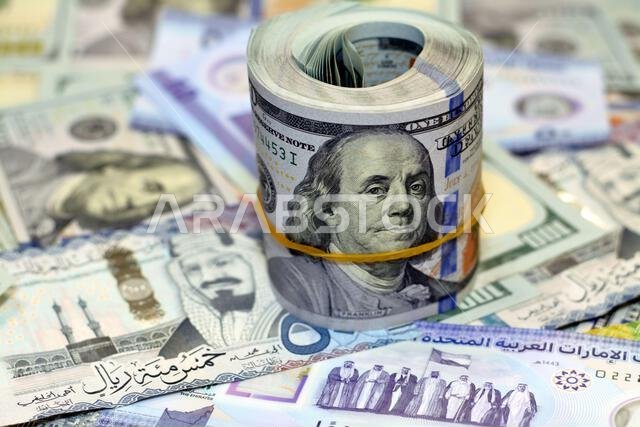 لفة نقود أمريكية عليها شريط، وكومة من أوراق الدولار الأمريكي، وأوراق نقدية أمريكية مع أوراق نقدية من الريال السعودي والإمارات الجديدة. لفة نقود أمريكية عليها شريط، وكومة من أوراق الدولار الأمريكي، وأوراق نقدية أمريكية مع أوراق نقدية من الريال السعودي والإمارات الجديدة.