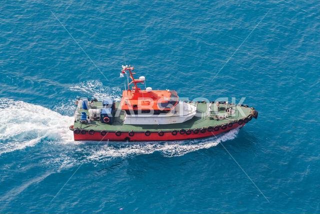Pilot boat with red hull and green deck is on the way. Red Sea, Jeddah port, Saudi Arabia