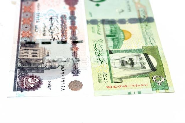 وجهان لعملة ورقية قديمة من فئة ٥٠ ريال سعودي مع ورقة نقدية من فئة ٥٠ جنيه مصري معزولة على خلفية بيضاء، تركيز انتقائي على الجنيه المصري