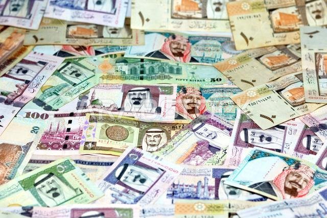 Background of a pile of Saudi Arabia riyals banknotes money bills of different values from different times, selective focus of a stack of Saudi riyals