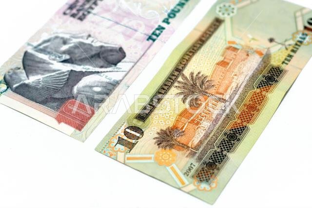 الوجه الخلفي لورقة نقدية قديمة من فئة 10 ريالات سعودية مع ورقة نقدية من فئة 10 جنيهات مصرية معزولة على خلفية بيضاء، تركيز انتقائي على الوجه الخلفي لورقة نقدية قديمة من فئة 10 ريالات سعودية مع ورقة نقدية من فئة 10 جنيهات مصرية معزولة على خلفية بيضاء، تركيز انتقائي على