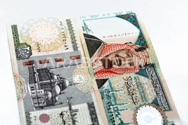 Obverse sides of Saudi Arabia 20 twenty riyals banknote with 20 LE twenty Egyptian pounds bill isolated on a white background, Selective focus of Egyp Obverse sides of Saudi Arabia 20 twenty riyals banknote with 20 LE twenty Egyptian pounds bill isolated on a white background, Selective focus of Egyp